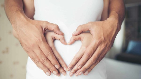 Pregnant Woman and Her Husband hand showing heart shape.